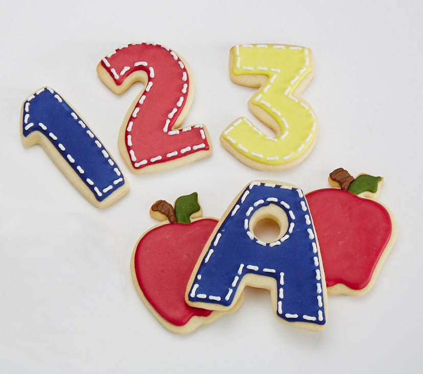 Decorative cookies shaped like numbers, letters, and apples on a white background