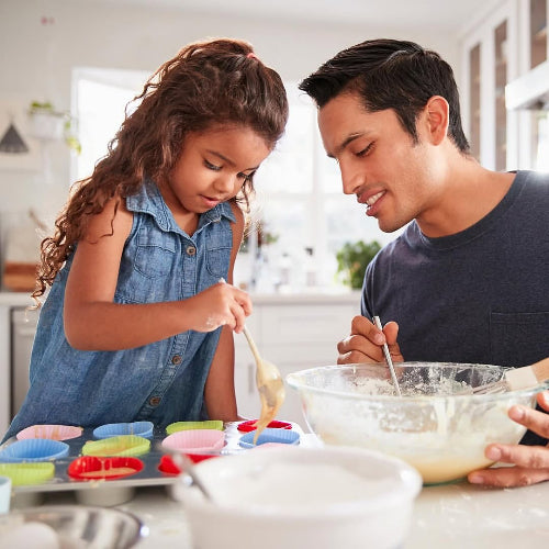 Little girl and father making cupcakes