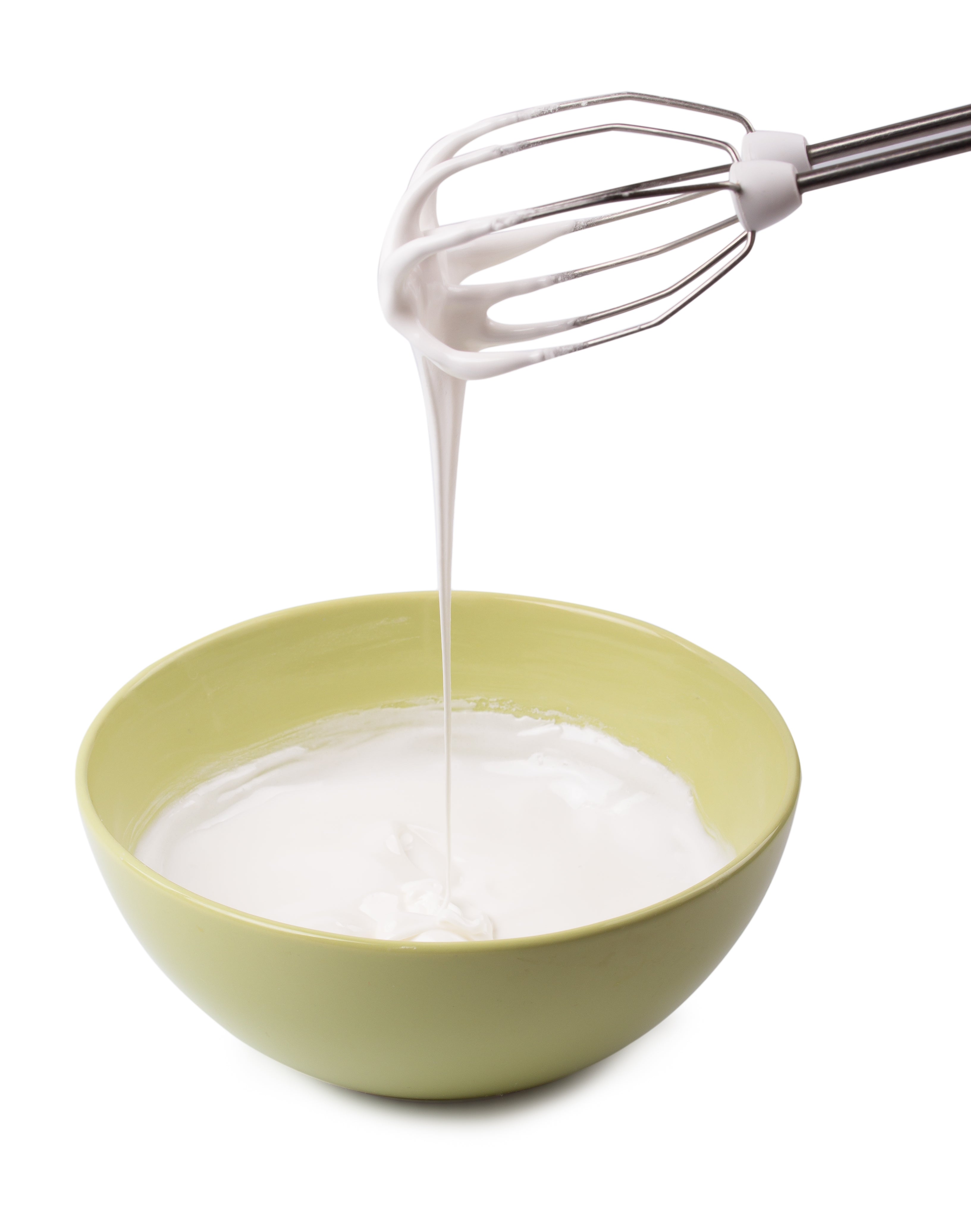 Whisking cream into a green bowl on a white background